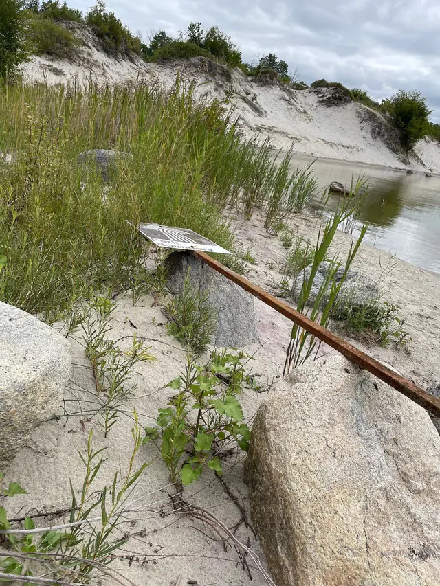 Fallen park boundary sign on the lake shore